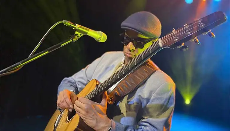 raul midon playing guitar in the spotlight on stage 768x439