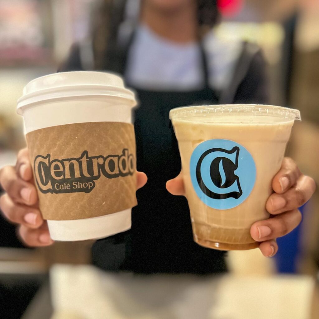 a person holding two cups of coffee from Centrado Cafe in Burtonsville, MD