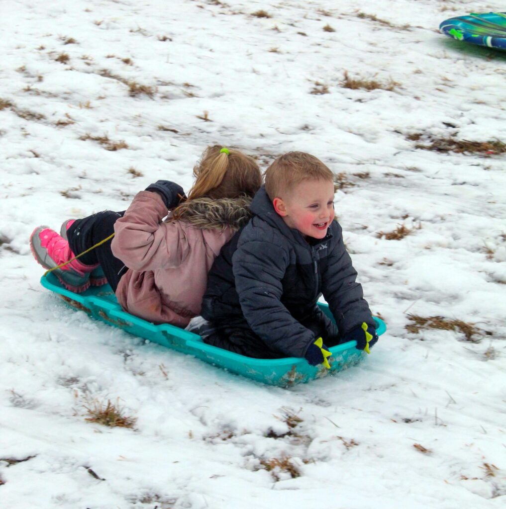 kids sledding down a hill of snow