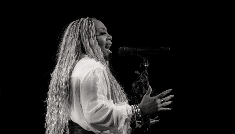 lalah hathaway wearing a white blouse and performing at the mic 768x439